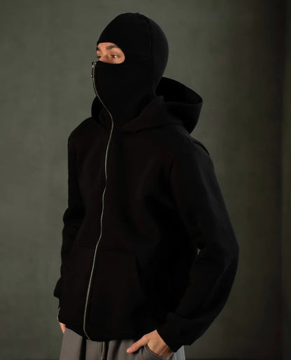 Model wearing oversized Ninja Hoodie with face mask fully zipped for smog protection in Lahore.